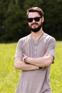 smiling-young-male-posing-meadow-with-arms-crossed